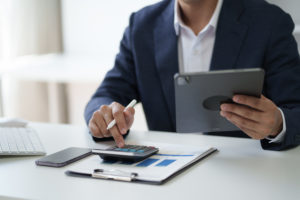 Close Up View Of Businessman Working In The Office Room While Using Calculator In The Office Room. - A J e Oliveira Associados | Advocacia em São Paulo